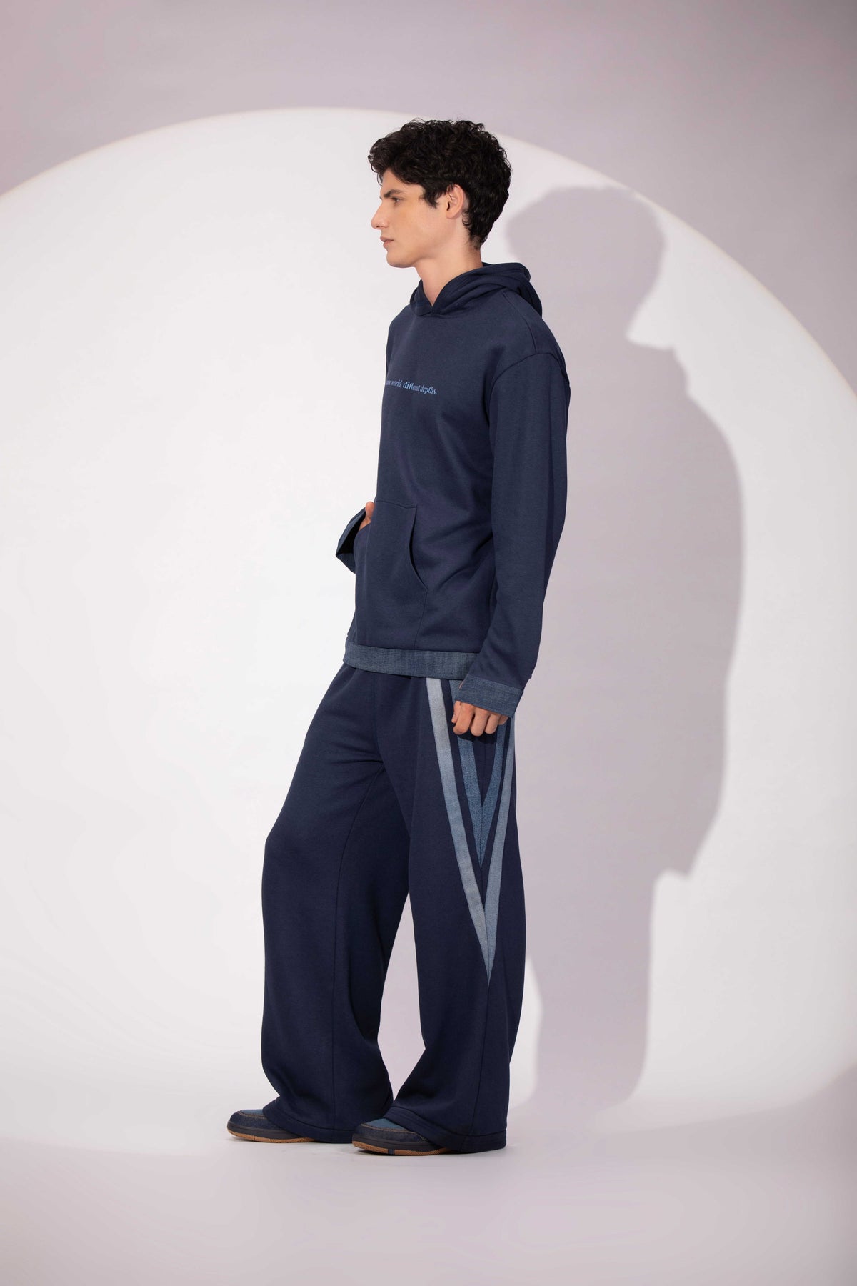 Side view of Shared World Hoodie showing its deep blue silhouette and denim detail